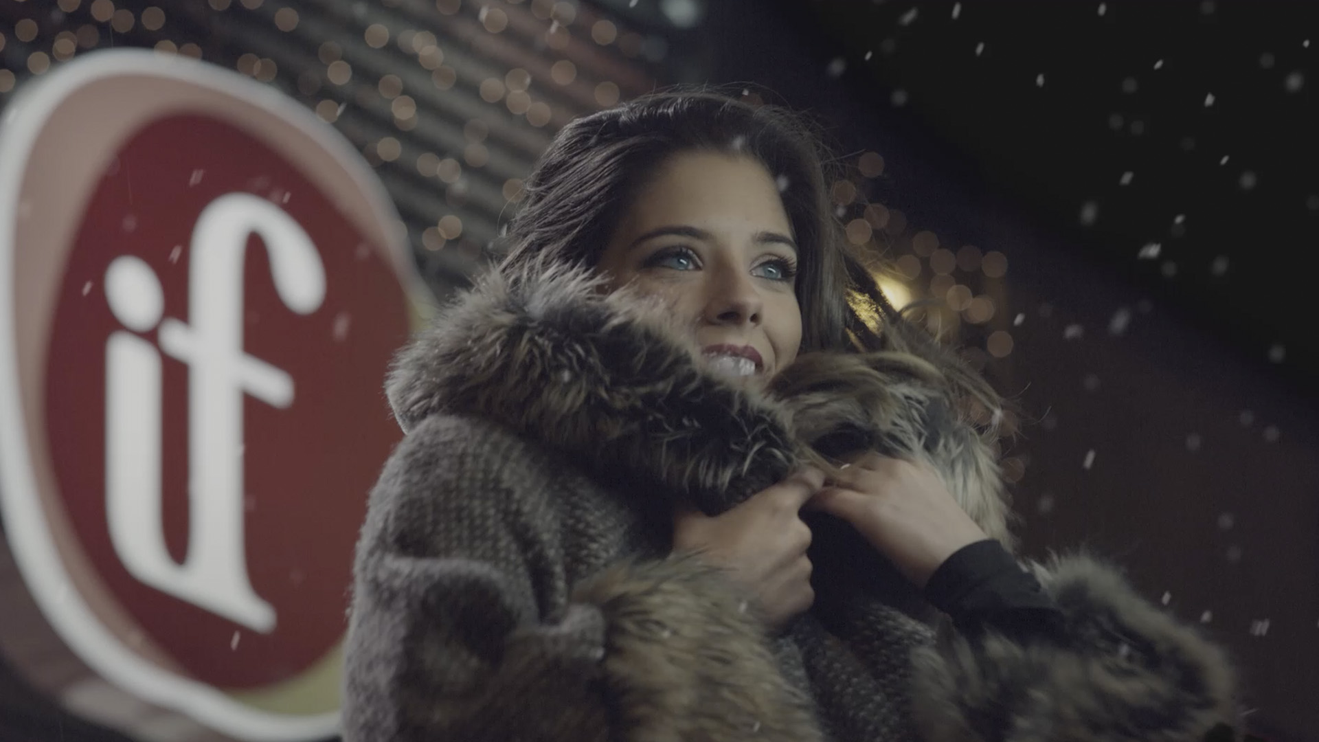 Chica en la nieve con el logo de perfumerías If detras de ella.